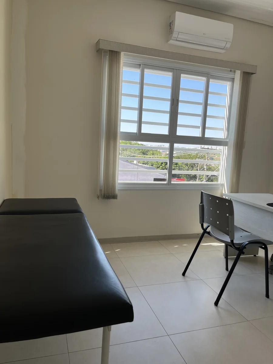 Sala de atendimento com maca, mesa e ar-condicionado